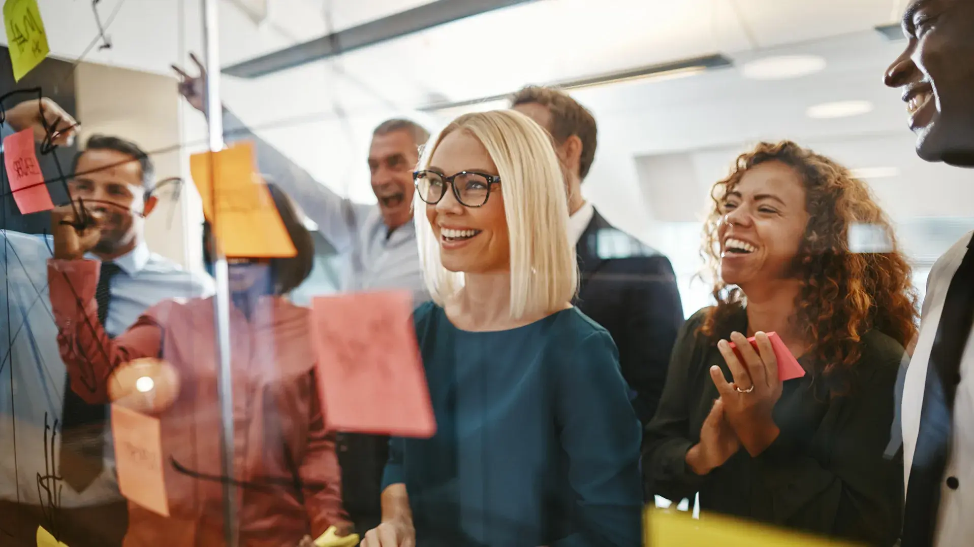 businesspeople brainstorming with notes on a glass wall
